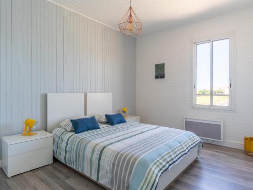 une chambre avec un lit avec des oreillers bleus et une fenêtre dans l'établissement Superbe T3 rénové à 200m de l'océan avec terrasse et parking privatif - FR-1-50-74, à Mimizan