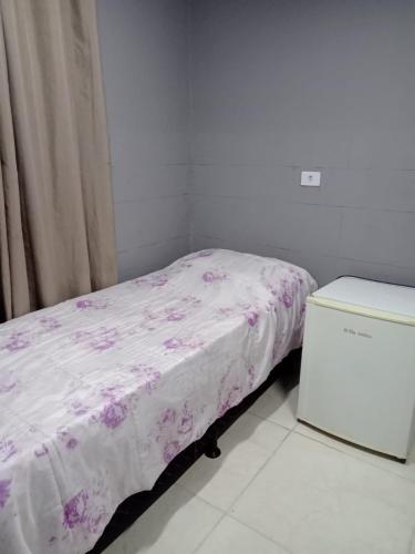 Dormitorio pequeño con cama con manta rosa en Pousada vithoria en Pinhais