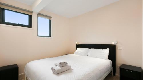 a bedroom with a white bed with two towels on it at Snowtel 4 in Mount Hotham