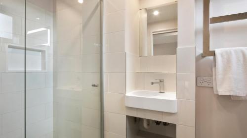 a white bathroom with a sink and a mirror at Snowtel 4 in Mount Hotham