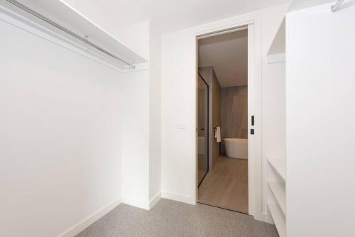 un couloir blanc avec une porte menant à une salle de bains. dans l'établissement Modern 3BR Getaway next to Chadstone, à Oakleigh