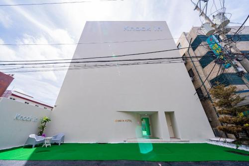 un edificio blanco con suelo verde y 2 sillas en Knockin Hotel Daejeon by Aank, en Daejeon