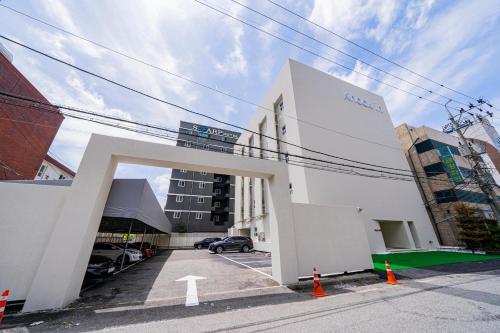 a white building with an arch in a parking lot at Knock In Hotel Daejeon by ANNK in Daejeon