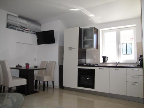 a kitchen with white cabinets and a table and a window at Apartments Marina in Zadar