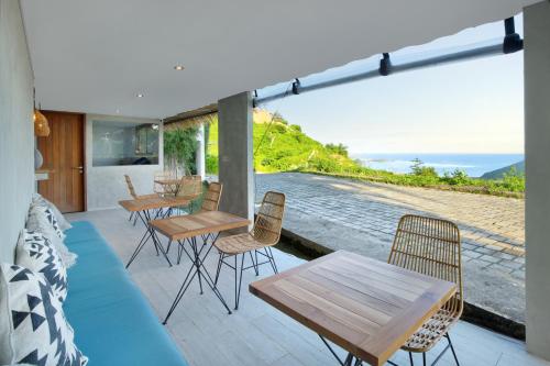 a patio with tables and chairs and a view of the ocean at Telescope Villas Lombok in Kuta Lombok