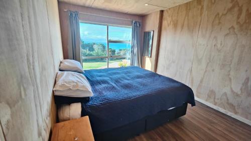 a bedroom with a blue bed and a window at Spectacular Moana Views in Riverton