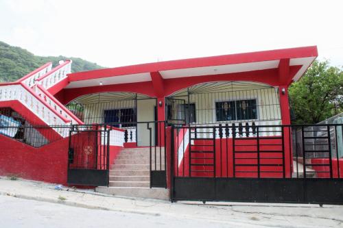 ein rotes Gebäude mit einer Treppe und einer roten Tür in der Unterkunft Aparta Hotel Los Deisy in Los Patos