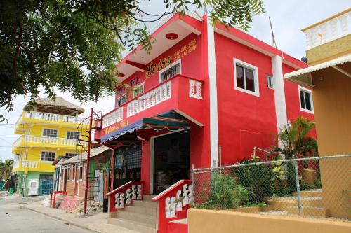 a red building on the side of a street at Aparta Hotel Los Deisy in Los Patos