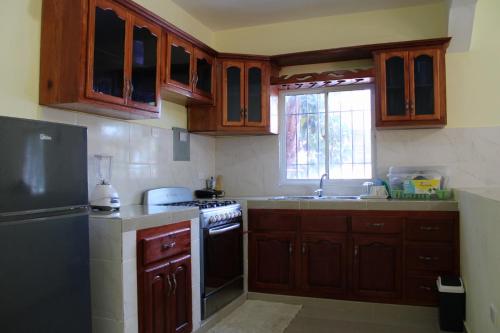eine Küche mit Holzschränken, einem Herd und einer Spüle in der Unterkunft Aparta Hotel Los Deisy in Los Patos