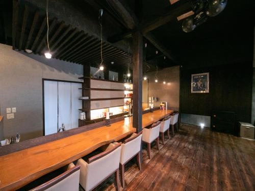 a long bar in a room with white chairs at AsoTsuruya in Aso