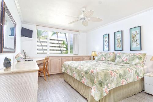 Schlafzimmer mit einem Bett, einem Schreibtisch und einem Fenster in der Unterkunft Oceanfront Condo Wrap-Around Lanai Almost Hanging Over The Ocean -Hale Kona Kai 313 by Casago Kona in Kailua-Kona