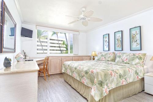 カイルア・コナにあるOceanfront Condo Wrap-Around Lanai Almost Hanging Over The Ocean -Hale Kona Kai 313 by Casago Konaのベッドと机と窓のある寝室