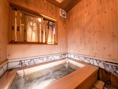 a hot tub in a room with a window at AsoTsuruya in Aso