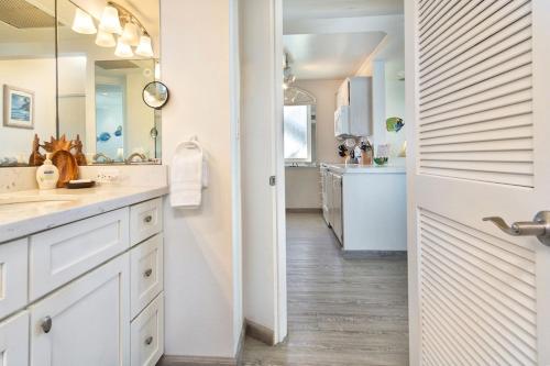 ein weißes Badezimmer mit einem Waschbecken und einem Spiegel in der Unterkunft Oceanfront Condo Wrap-Around Lanai Almost Hanging Over The Ocean -Hale Kona Kai 313 by Casago Kona in Kailua-Kona