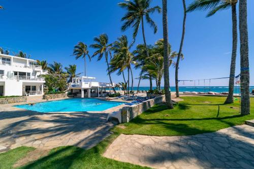 a resort swimming pool with palm trees and the ocean at WOW location Kite Beach Oceanfront 2 Bedroom Patio and Pool in Cabarete