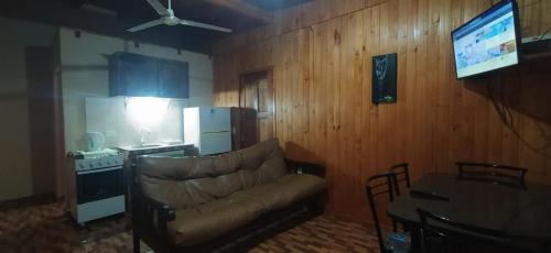 a living room with a couch and a table and a kitchen at Cabañas cerella in Puerto Iguazú