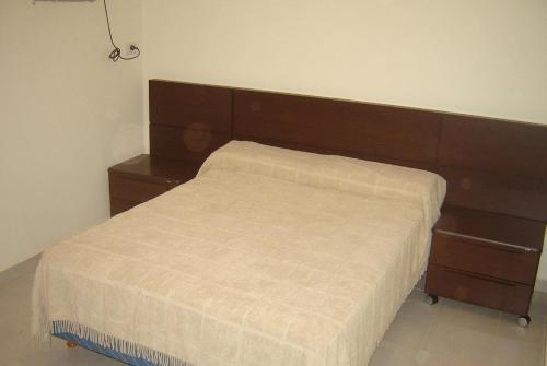 1 cama con cabecero de madera en un dormitorio en Departamentos Donovan en Resistencia