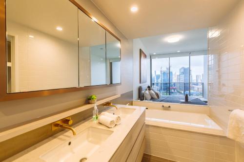 a bathroom with a sink and a tub and a window at Multi Million River View 3BD Penthouse at SouthBank in Brisbane