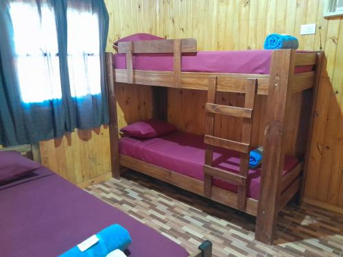 a room with two bunk beds with purple sheets at Cabañas cerella in Puerto Iguazú