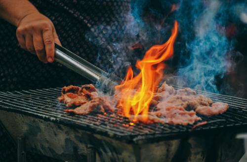 a person cooking meat on a grill with flames at Bardia Wild Side Hotel in Bhurkīā