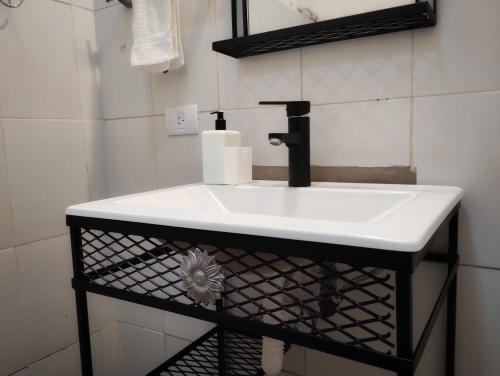 a white sink in a bathroom with a black stand at Hospedaje DCB in Capilla del Monte