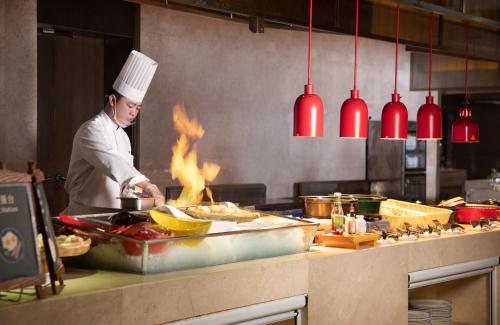 a chef preparing food in a kitchen with flames at The Yun Hotel Hankou in Wuhan