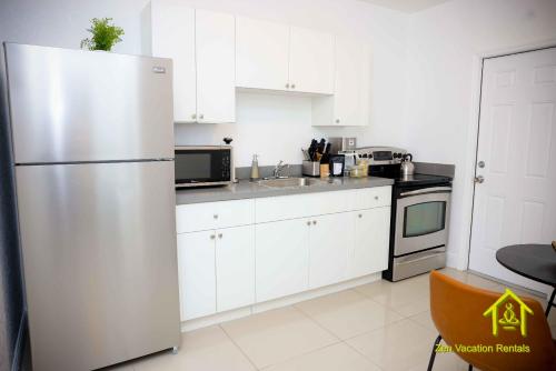 a kitchen with white cabinets and a refrigerator at BH Club by Zen Vacation Rentals 2BR 1BA in Miami Beach