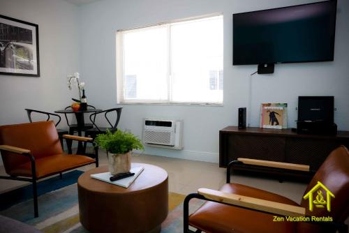 sala de estar con TV, sillas y mesa en BH Club By Zen Vacation Rentals, en Miami Beach