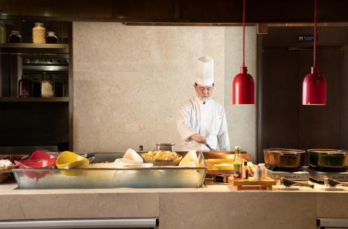 a chef standing in a kitchen preparing food at The Yun Hotel Hankou in Wuhan