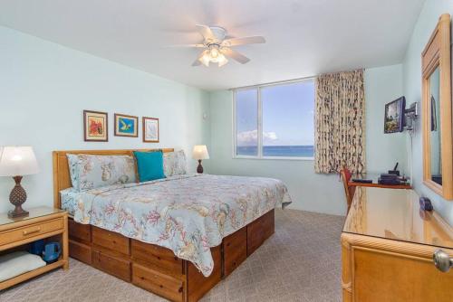 a bedroom with a bed with a ceiling fan and a window at Beautifully Renovated Oceanfront Condo w/ breathe taking Views! - Hale Kona Kai 302 in Kailua-Kona