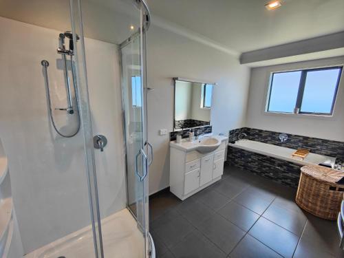 een badkamer met een douche, een wastafel en een bad bij Gorgeous in the Glen in Kennington