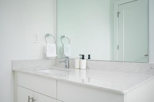 a white bathroom with a sink and a mirror at Downtown New-Built Roof-top balcony City View 525Pkwy419 in Atlanta