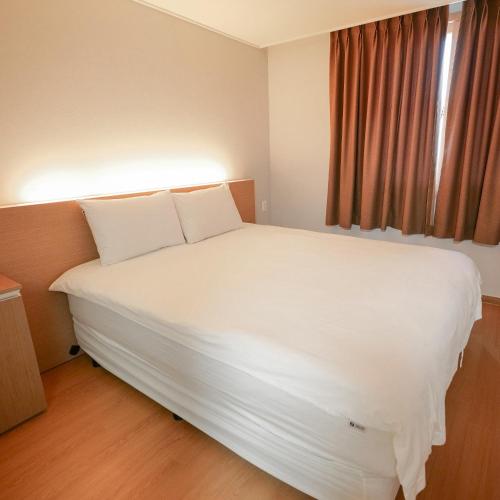 a large white bed in a room with a window at Residence Hotel K Okpo in Geoje 