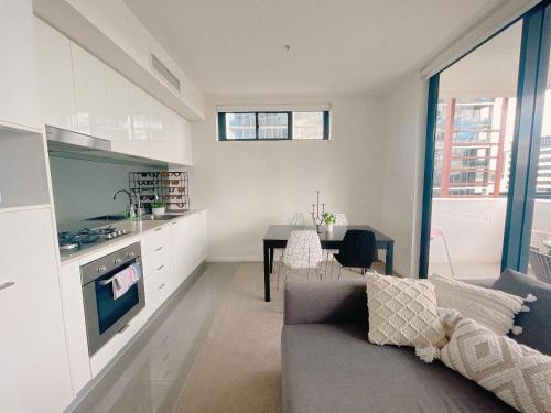 a kitchen and living room with a couch and a table at Cosy and Stylish 1 BD Serviced Apt at SouthBank in Brisbane