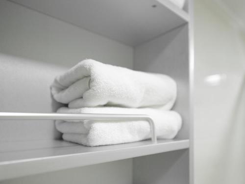 a pile of towels on a shelf in a bathroom at Residence Hotel K Okpo in Geoje 