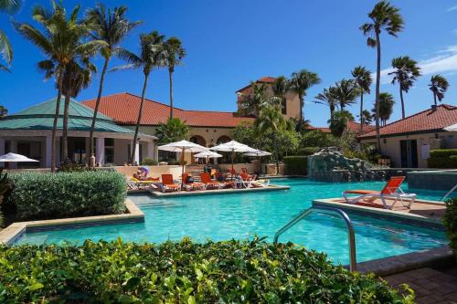uma piscina num resort com cadeiras e palmeiras em luxurious house with private pool in tierra del sol Resort&Golf em Palm-Eagle Beach