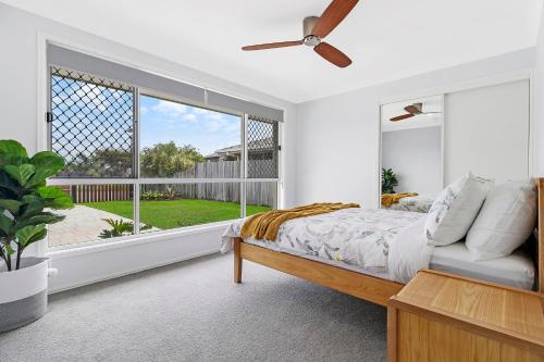 a bedroom with a bed and a large window at Breathtaking 4BR Resort like House Right Near Wurtulla Beach With Infinity Pool in Kawana Waters