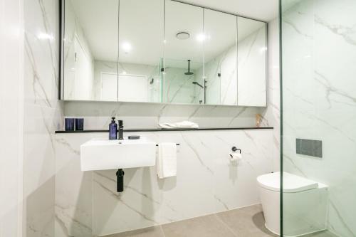 a white bathroom with a sink and a toilet at Modern 2BR Apartment near Wollongong Beach in Wollongong
