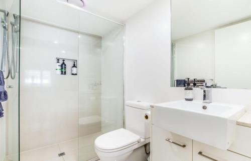 a white bathroom with a shower and a toilet and a sink at Luxurious 3BDR Townhouse in Great Location in Brisbane