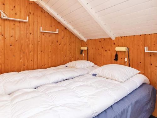 a large bed in a room with wooden walls at Holiday home Stubbekøbing III in Stubbekøbing