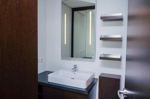 y baño con lavabo blanco y espejo. en Nusa Dua Penthouse en Nusa Dua