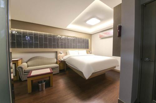 ein Hotelzimmer mit einem Bett und einem Sofa in der Unterkunft Sugar Hotel in Gyeongju