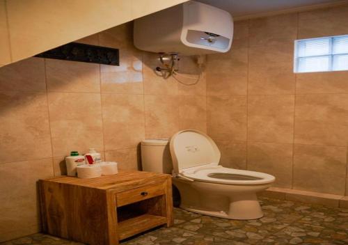 a bathroom with a toilet and a wooden table at Adipana Bungalow-Balinese Room in Ubud