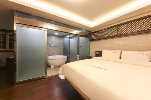 1 dormitorio con 1 cama grande y bañera en Sugar Hotel, en Gyeongju