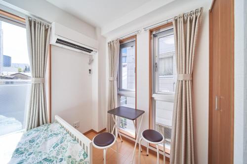 a bedroom with a bed and two chairs and a window at Yuzuki Dome Osaka Kujo in Osaka