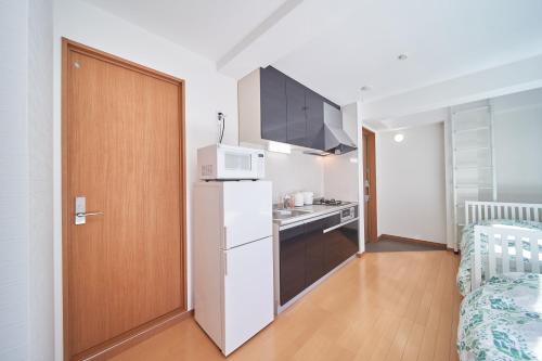 a kitchen with a white refrigerator and a microwave at Yuzuki Dome Osaka Kujo in Osaka