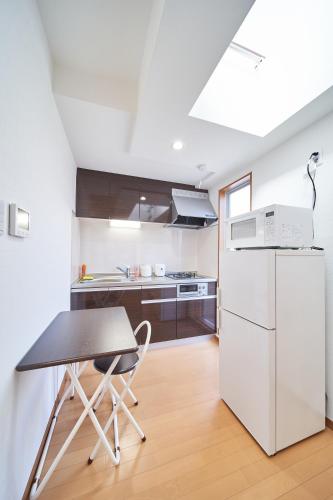 a kitchen with a table and a refrigerator at Yuzuki Dome Osaka Kujo in Osaka