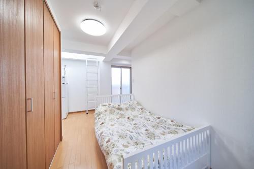 a bedroom with a bed and a crib in it at Yuzuki Dome Osaka Kujo in Osaka