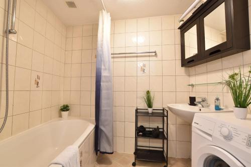 a bathroom with a tub and a sink and a washing machine at Hidden Gem in Central Innsbruck with free Parking in Innsbruck