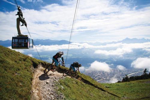 two people riding bikes on a hill with a ski lift at Hidden Gem in Central Innsbruck with free Parking in Innsbruck
